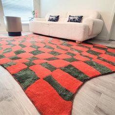 an orange and green rug in the middle of a living room with a white couch