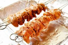 several skewers of meat sitting on top of aluminum foil