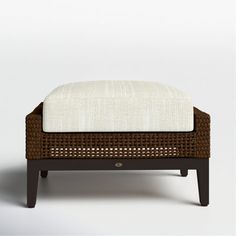 the foot stool is made out of wicker and has a white cushion on it