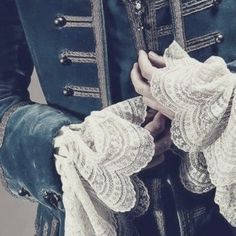 a close up of a person wearing a blue jacket and white lace trimmings