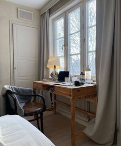 a desk with a laptop on top of it next to a window in a bedroom