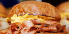 a bacon and egg sandwich is shown on a plate with other food items in the background