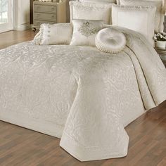 a bed with white comforters and pillows in a room