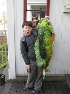 a young boy holding up a large fish