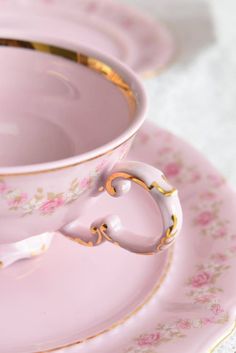 a pink tea cup and saucer with gold trim