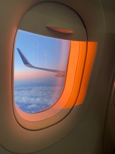 an airplane window with the view of clouds and blue sky from it's seat