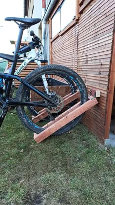 a bike leaning against the side of a building next to a bicycle rack with wheels on it