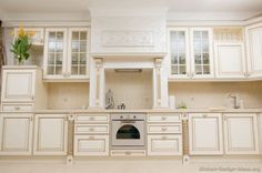 a kitchen with white cabinets and an oven in the center is decorated with yellow daffodils