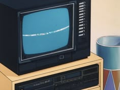 an old television sitting on top of a wooden table next to a lamp and vase