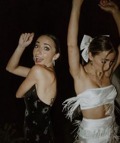 two young women dressed in white and black dancing with their arms up to the side