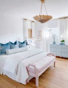 a white bed with blue pillows in a bedroom