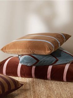 three pillows stacked on top of each other in front of a white wall and floor