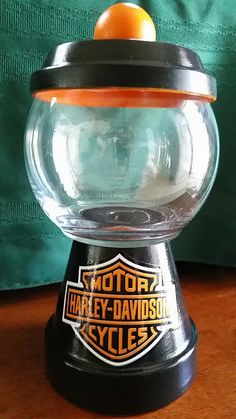 an orange sitting on top of a glass bowl with harley davidson style lettering and logo