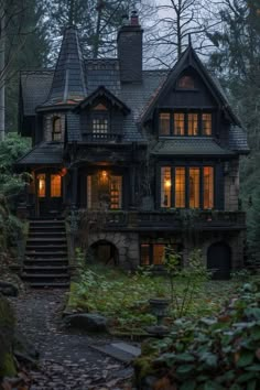 a house in the woods with stairs leading up to it and lights on at night