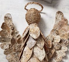 an old wooden angel ornament hanging on a wall with twine baskets attached to it