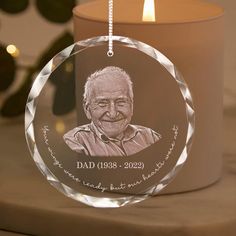 a glass ornament with a photo of a man on it next to a candle