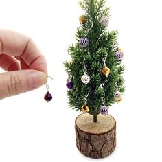 a small christmas tree with ornaments on it is being held by a person's hand