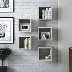 a white brick wall with some bookshelves and pictures on the wall above it