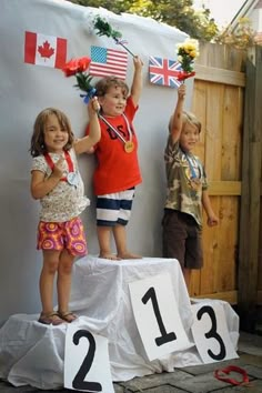 two young children standing on top of a podium with their hands up in the air