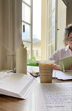 a woman sitting at a table with an open book and coffee cup in front of her