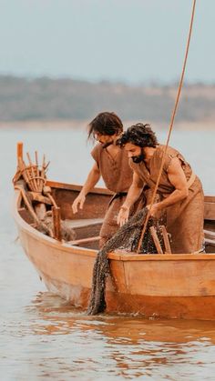 two people in a boat on the water with one holding a fishing pole and another reaching for something