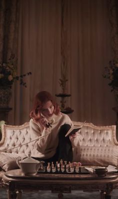 a woman sitting on top of a couch next to a chess board