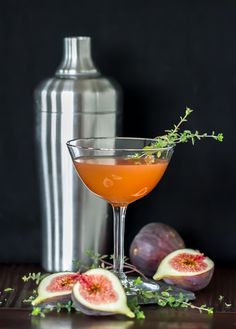 a glass filled with liquid next to some figs