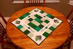 a wooden table topped with a green and white quilted placemat sitting on top of a wooden chair