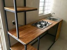 a stove top oven sitting under a window next to a wooden shelf filled with shelves