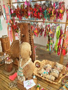 an assortment of items for sale on a table with ribbons hanging from the ceiling and in front of them is a teddy bear