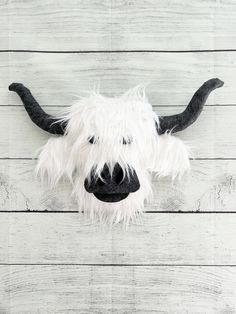 a white and black stuffed animal head on a wooden wall with long hair hanging from it's side