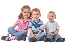 three children are sitting on the floor and smiling