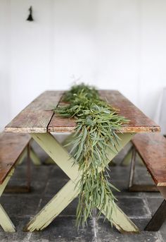 a wooden table topped with lots of greenery