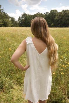 This is a white sleeveless v neck dress with a ruffle detail on the shoulder. The model is wearing a size small Feminine White V-neck Ruffle Dress, Summer Sleeveless V-neck Dress With Ruffles, Cotton V-neck Dress With Ruffles, White V-neck Ruffle Dress For Day Out, V-neck Sleeveless Dress With Ruffles For Day Out, Feminine Dress With Ruffled Straps For Day Out, Summer Ruffle Sleeve Dress For Casual Occasions, Sundress With Ruffled Straps For Day Out, Feminine Cotton Dresses With Ruffled Straps