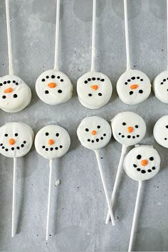 marshmallows with frosting and orange noses are arranged in the shape of a snowman