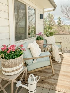 a porch with two chairs and flowers on the back deck, next to a potted plant