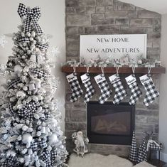 a decorated christmas tree in front of a fireplace with stockings hanging from the mantel