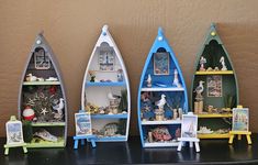 three canoe shaped shelves with pictures and figurines on them in front of a wall