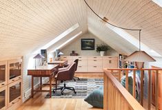 an attic office with wooden floors and white walls, along with a desk in the corner