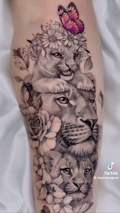 a woman's leg with tattoos on it and two lions in the middle, surrounded by flowers