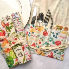 the napkins are wrapped in colorful fruit designs and tied with twine ribbons, along with silverware