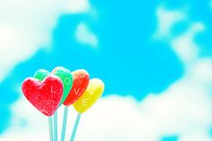 three lollipops with the word love spelled on them in front of a blue sky