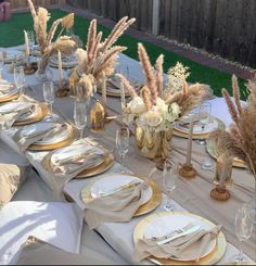 the table is set with white and gold plates, napkins, silverware, and flowers