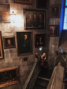 a woman is sitting on the stairs in front of paintings and pictures hanging on the wall