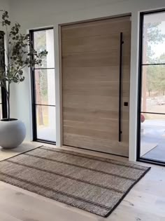 a white vase sitting on top of a rug in front of a wooden entry door