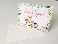 a thank you card with an image of deer and other animals on it, in front of a white envelope