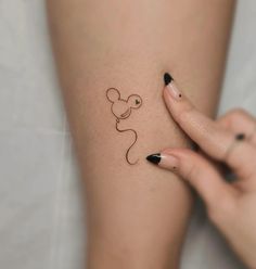 a woman's arm with a small mouse tattoo on the left side of her leg