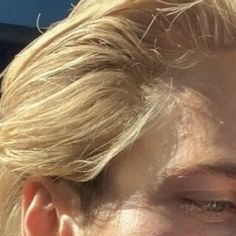 a close up of a person with blonde hair and an earring in the sun