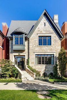 a large brick house with many windows and steps leading up to the front door on a sunny day