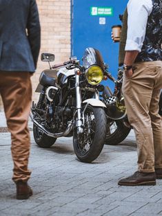 two men standing next to a parked motorcycle